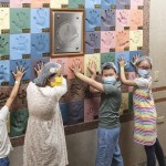 孩子們將手掌輕貼在紀念牆上的手印上，逗趣地模擬烘焙職匠們，落下手印的經典時刻。