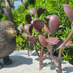 一株株銅葉舒展枝姿，在陽光下閃耀生命的光澤，鳥兒靜靜守望，為街道增添自然的詩意。