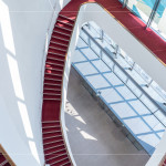 光線穿透玻璃，灑落在蜿蜒的紅毯旋梯上，從二樓延伸至五樓的曲線，讓建築不再只是結構，更是一場光的藝術。